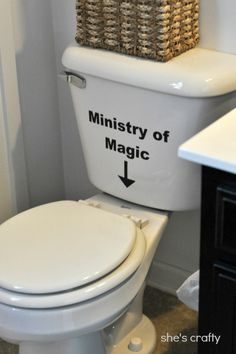 a white toilet sitting inside of a bathroom next to a sink and counter top with a basket above it