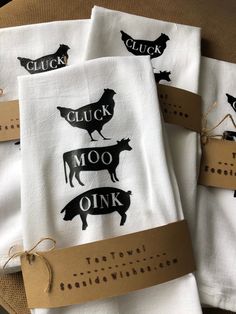 three flour towels with black farm animals on them, tied to brown paper tags that read chuck moo oink