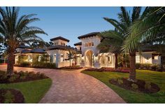 a large white house with palm trees in the front yard and walkway leading to it