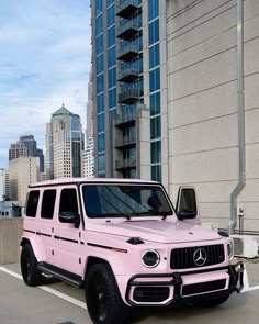 a pink mercedes g - class is parked in front of a tall building with skyscrapers