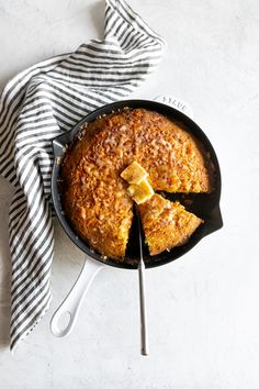 a skillet with some food in it and a striped towel on the table next to it