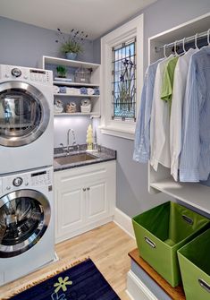 a washer and dryer in a small room with clothes hanging on the rack