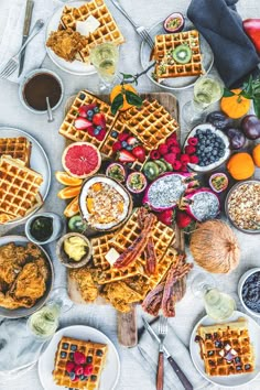 a table topped with waffles, fruit and other foods