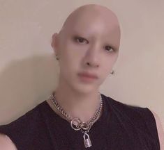 a bald man wearing a necklace with a key on it