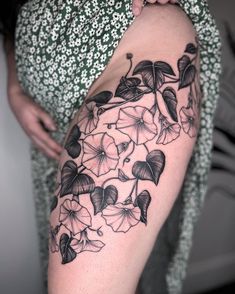 a woman's thigh with black and white flowers on the bottom half of her leg