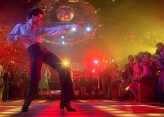 a man and woman dancing on a dance floor with disco balls in the back ground