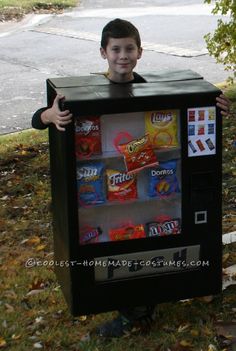 a young boy is holding up an old fashioned vending machine costume that he made for halloween