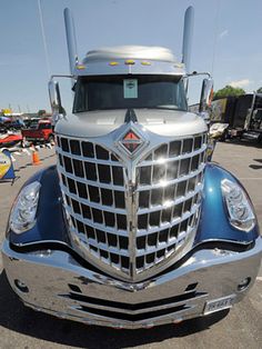 a large semi truck parked in a parking lot next to other cars and trucks behind it