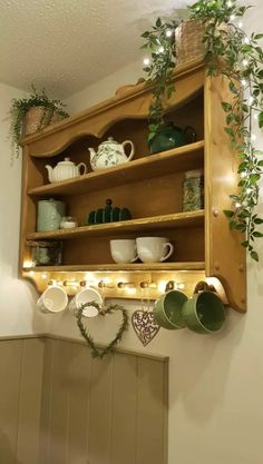 a wooden shelf filled with lots of dishes and greenery on top of it's shelves