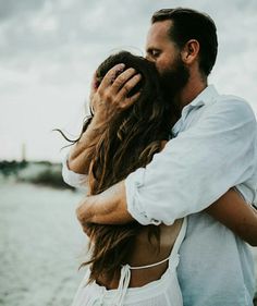 a man and woman embracing each other on the beach