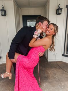 a woman in a pink dress and a man in a black suit kissing each other