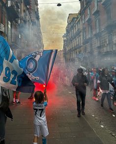 a small child holding a blue and white flag in the middle of a crowded street