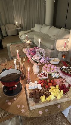 a table filled with desserts and candles on top of a wooden table next to a couch