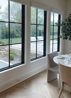 a dining room table and chairs with large windows