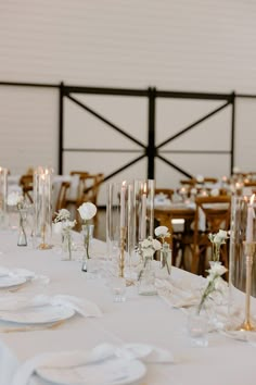 the table is set with white flowers and candles for an elegant wedding reception or special event