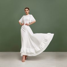 a woman is wearing a white dress with ruffles on the skirt and heels