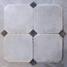 four white and black tiles on the floor with grey grouting in between them