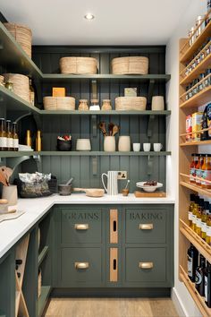 a kitchen with green cupboards and shelves filled with food, wine bottles and other items