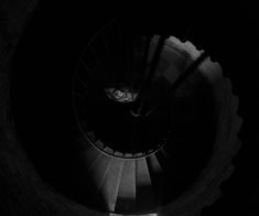 a spiral staircase in the dark with a person walking up it