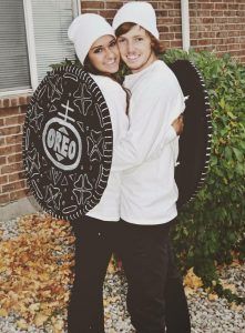 two people standing next to each other in front of a brick building holding a shield