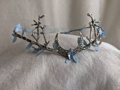 This gorgeous tiara features a filigree crescent moon, a sparkling opalescent blue crystal in the center, and branches on either side. Fallen sky blue leaves surround the flexible branch-like base. This piece is adjustable with a ribbon tie in the back. Choose between a silver moon and branches as pictured or bronze! Blue Adjustable Whimsical Headpiece, Whimsical Blue Adjustable Headpiece, Woodland Tiara, Kule Ting, العصور الوسطى, Idee Cosplay, Magical Jewelry, Coron, Head Piece