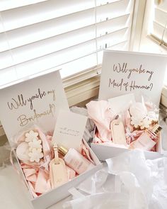 two white boxes filled with pink and white flowers on top of a bed next to a window