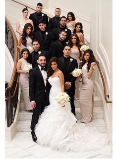 a large group of people in formal wear posing for a photo on the stairs at a wedding