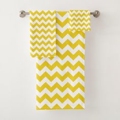 two yellow and white chevron towels hanging on a towel rack in front of a wall