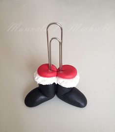 a pair of black and red shoes with white ruffles on them are attached to a metal holder