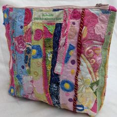 a multicolored patchwork purse with flowers and butterflies on the front is sitting on a white surface