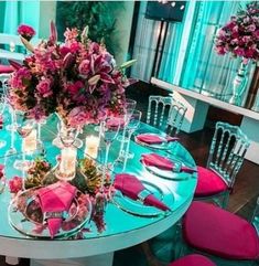 the table is set with pink flowers and place settings for four people to sit at