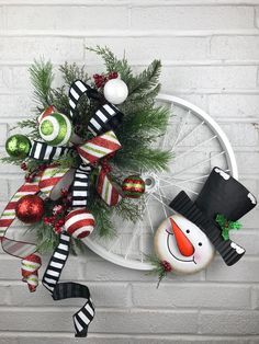 a christmas wreath with ornaments hanging on the side of a brick wall next to a snowman ornament