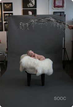 a baby is laying on top of a chair in front of a photo studio backdrop