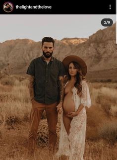 a pregnant woman standing next to a man wearing a cowboy hat in the desert with mountains behind her