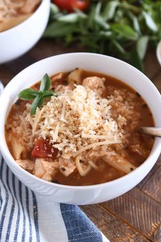 two white bowls filled with soup and topped with parmesan cheese