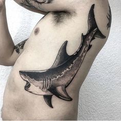 a man's stomach with a tattoo of a shark on the side and his arm