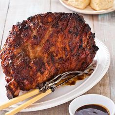 a large piece of meat sitting on top of a white plate next to dipping sauce