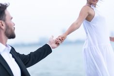 a man and woman holding hands by the water