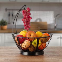 a wire basket filled with fruit on top of a wooden table next to a kitchen counter