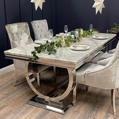 a dining room table set for four with white chairs and star decorations on the wall