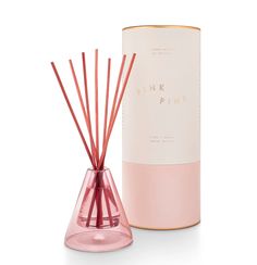 pink pine reeds in a glass vase next to a box with the lid open