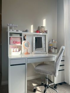 a white desk topped with a computer monitor and a mirror next to a gray chair