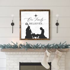 a christmas scene with stockings hanging from the mantel, and a framed nativity sign above it