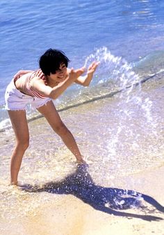 a woman in white shorts playing with a frisbee on the beach near the water