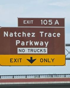 a brown and white sign that says natchez trace parkway no trucks exit only