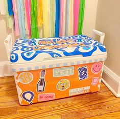 an orange and blue toy box with colorful curtains behind it