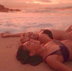 two women in bikinis laying on the beach