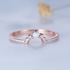 a rose gold ring with three diamonds on top and a white opal stone in the middle