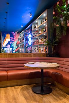 an empty restaurant with red booths and wooden tables in front of colorful wallpapers