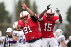 two football players in red and white uniforms are holding their hands up as they walk off the field